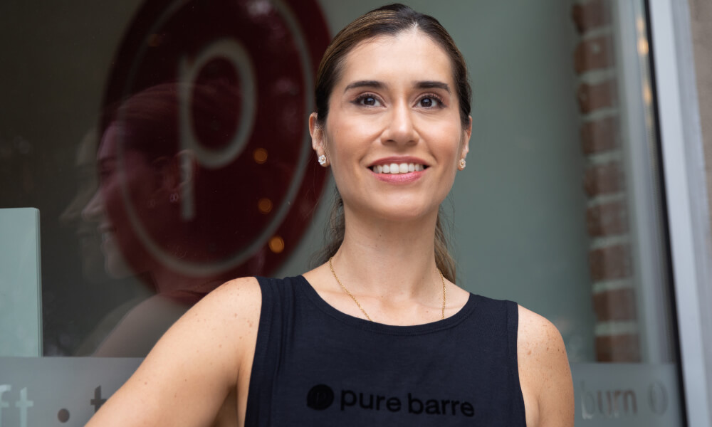 Person smiling in front of Pure Barre building